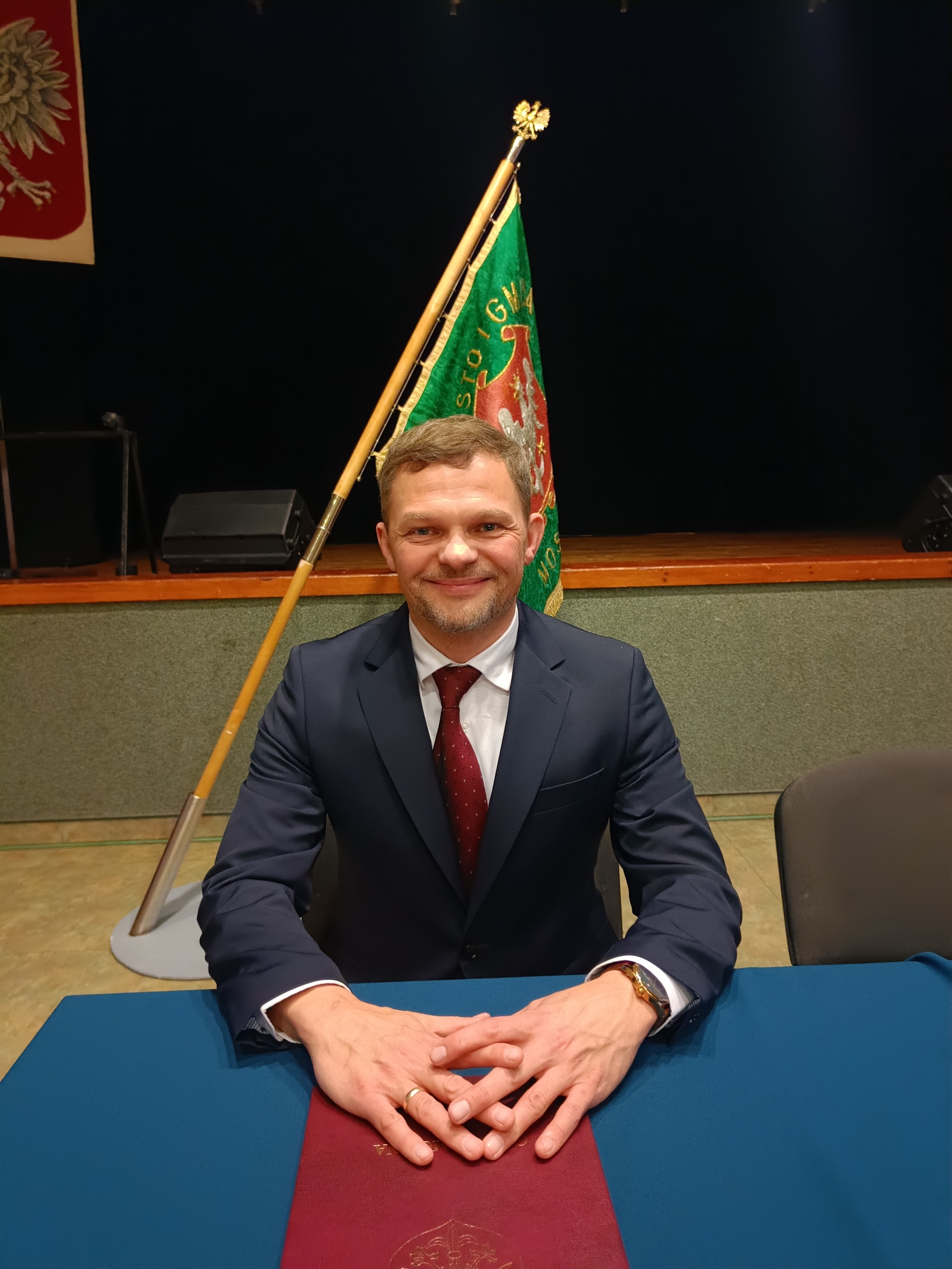 Radny Robert Borkiewicz na tle sztandaru Gminy Mosina